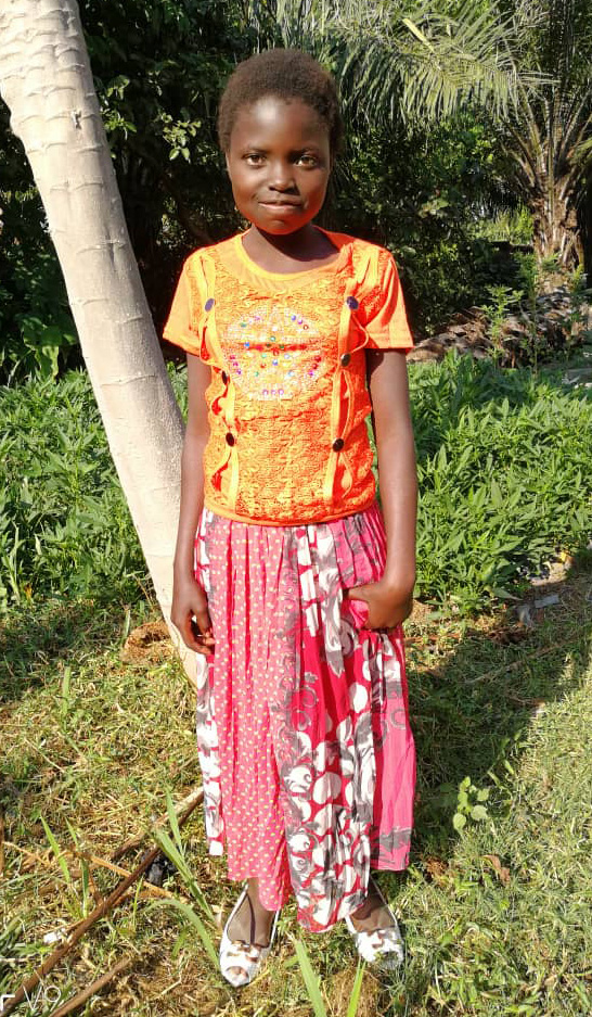 A young girl standing in front of a tree.