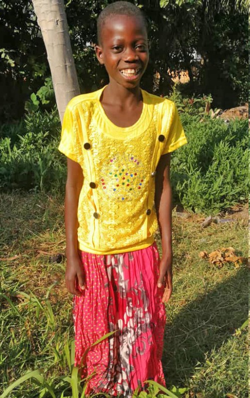A young girl in a yellow shirt and pink skirt.